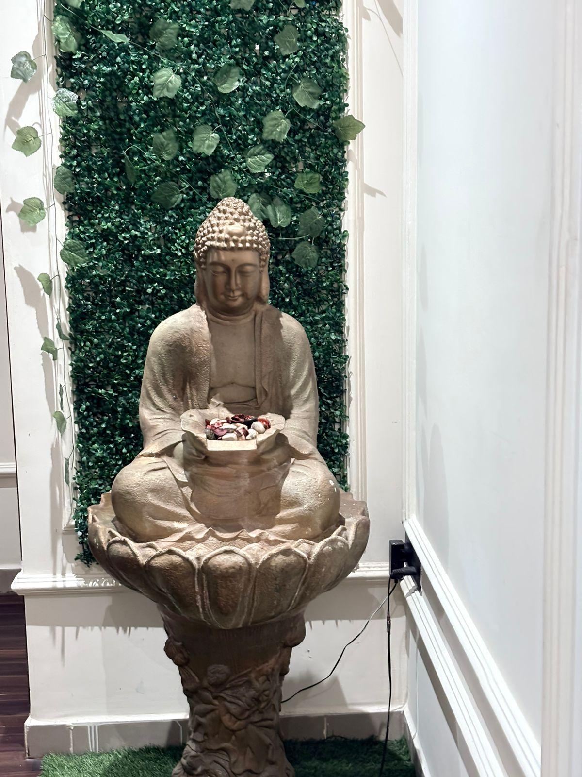 Buddha water fountain against a green wall at Jubilee Hills